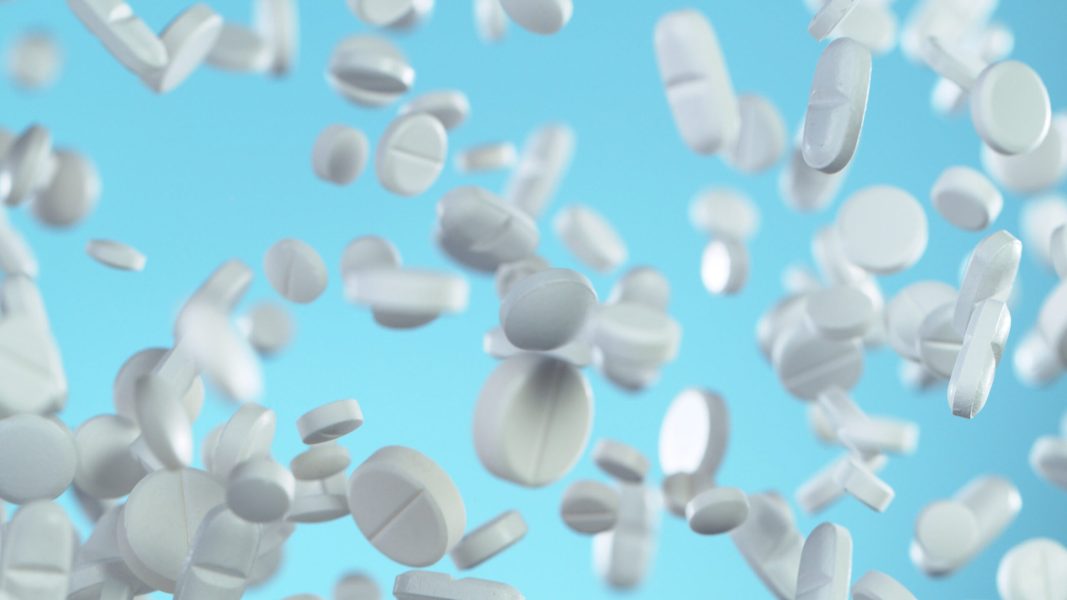 Freeze motion of flying group of white pills on blue soft background. Concept of health and medical